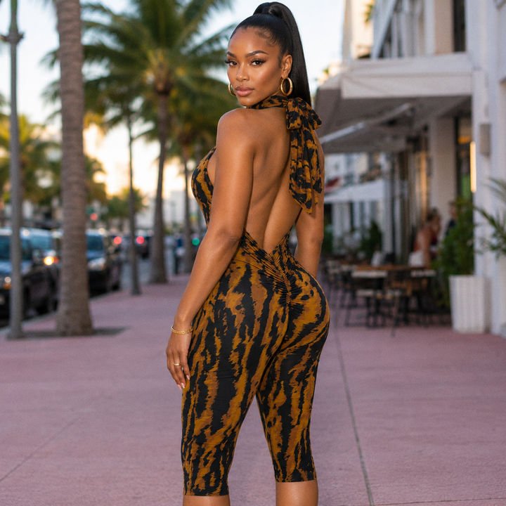 Rear three-quarter view of the Celine Capri showing the bare open back and halter bow tie in tiger stripe print